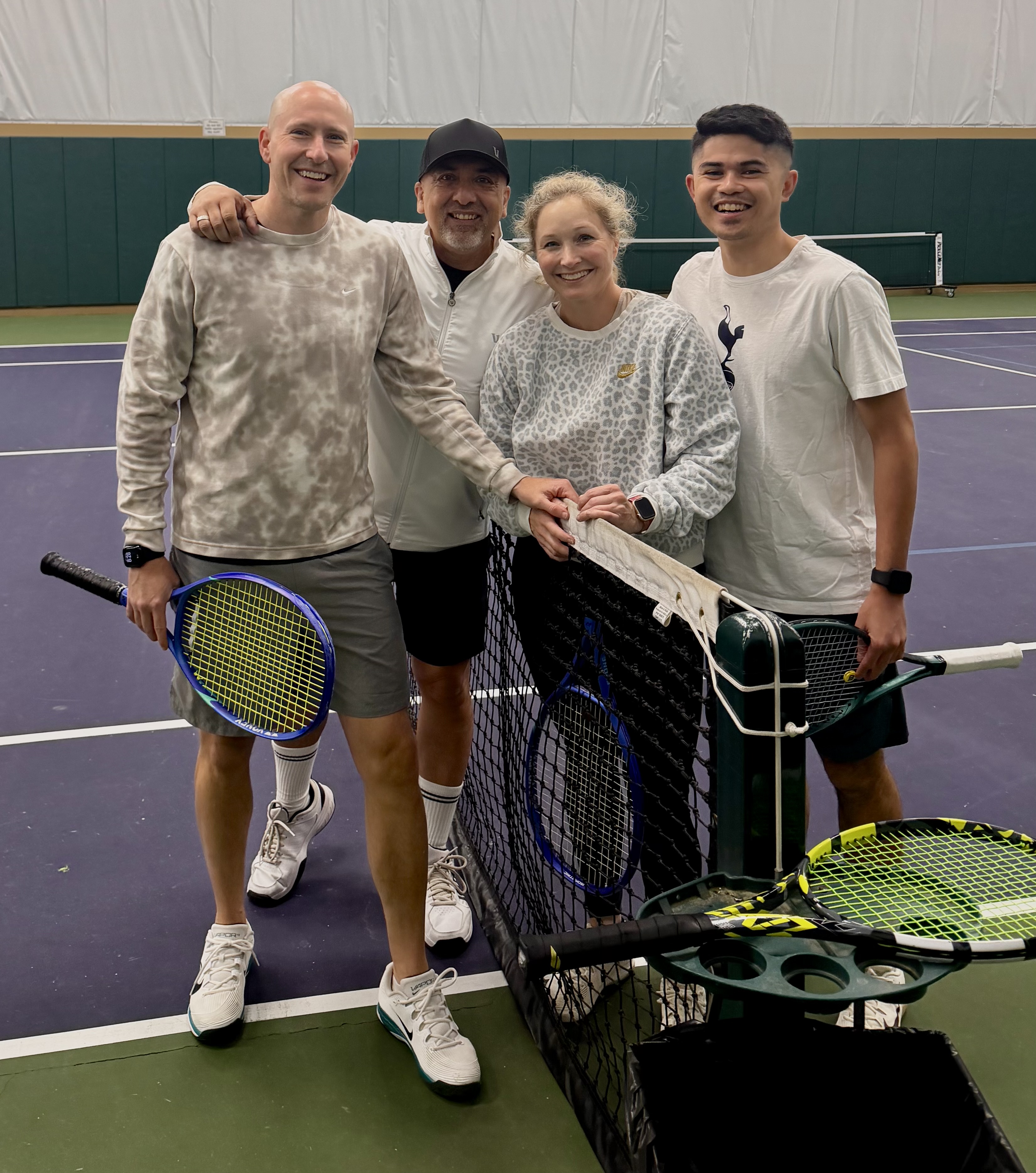 Coach Brian Guzman with students at the net on an indoor tennis court